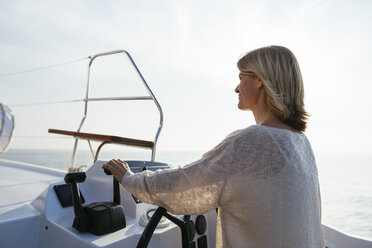 Mature woman navigating catamaran on a sailing trip - EBSF02637
