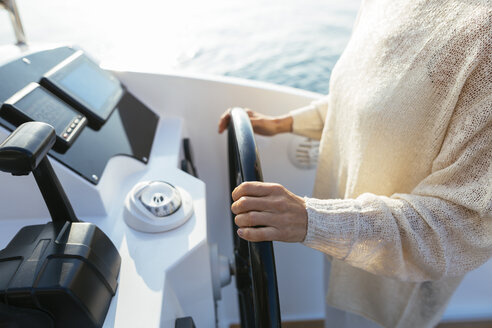 Mature woman navigating catamaran on a sailing trip - EBSF02639