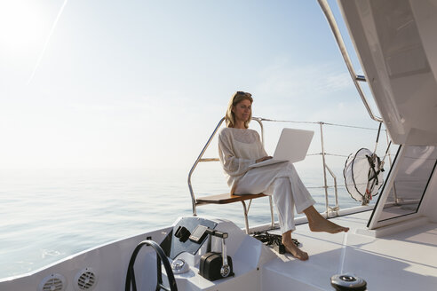 Woman sitting on catamaran, using laptop - EBSF02648