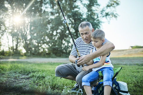 Grandfather and grandson fishing together at lakeshore - ZEDF01482