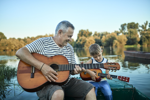 Großvater bringt seinem Enkel das Gitarrenspiel bei, lizenzfreies Stockfoto
