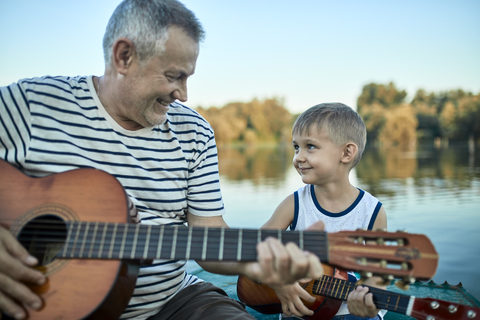 Großvater bringt seinem Enkel das Gitarrenspiel bei, lizenzfreies Stockfoto