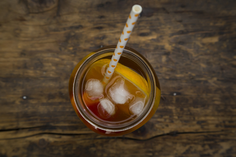 Glass of peach orange ice tea on wood stock photo