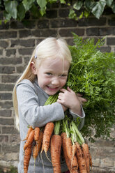 Ein junges Mädchen hält einen großen Strauß Karotten. - MINF00275