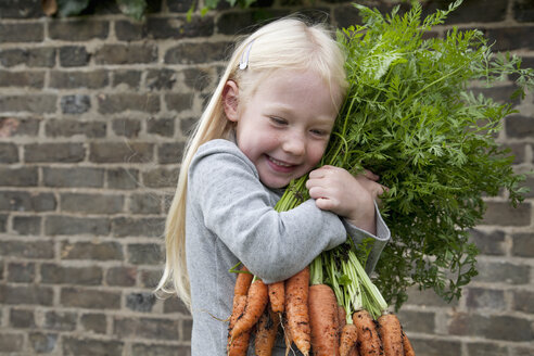 Ein junges Mädchen hält einen großen Strauß Karotten. - MINF00277