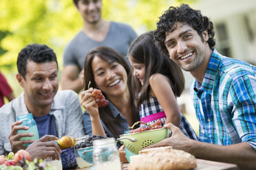 Adults and children around a table in a garden. - MINF00295