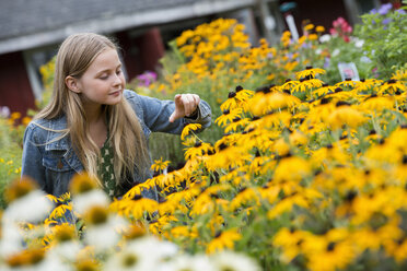 Eine biologische Gärtnerei, in der ein junges Mädchen die Blumen betrachtet. - MINF00320