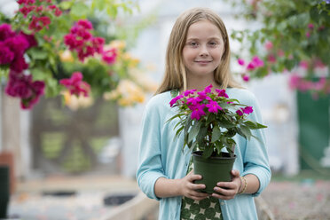 Ein junges Mädchen hält eine blühende Pflanze. - MINF00327