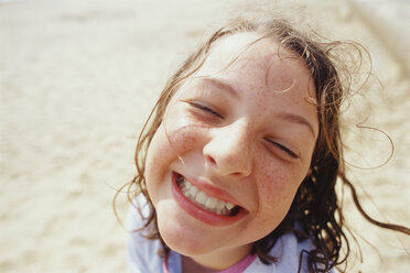 A young girl with a wide grin, eyes half closed, and wet hair outside in the rain. - MINF00331