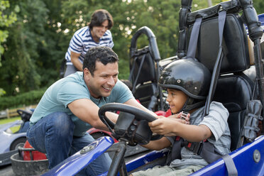 Jungen und Männer fahren Go-Kart auf einer Bahn. - MINF00354