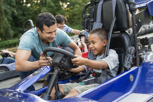 Jungen und Männer fahren Go-Kart auf einer Bahn. - MINF00355