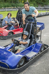 Jungen und Männer fahren Go-Kart auf einer Bahn. - MINF00356