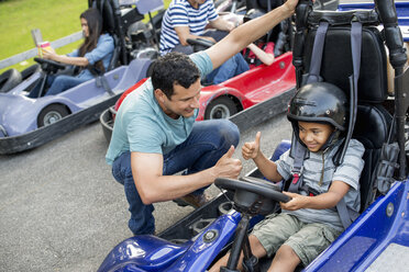 Jungen und Männer fahren Go-Kart auf einer Bahn. - MINF00357