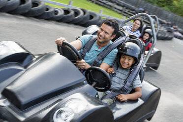 Jungen und Männer fahren Go-Kart auf einer Bahn. - MINF00358