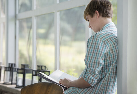 Ein junger Mensch sitzt und liest ein Buch. - MINF00394