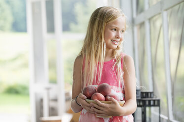 Ein junges Mädchen mit einem Arm voller frischer Pfirsiche. - MINF00400