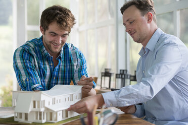 Zwei Männer betrachten ein Architekturmodell eines Hauses. - MINF00401