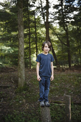 Ein Junge steht auf einem schmalen Baumstamm, balanciert und geht über die Planke. - MINF00430