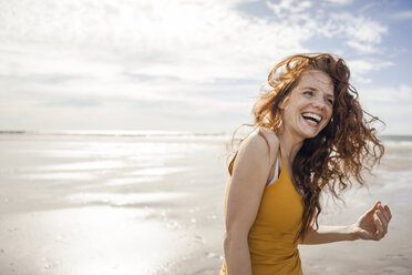 Netherlands, Zeeland, portrait of laughing redheaded woman on the beach - KNSF04192