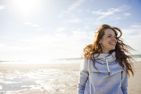Netherlands, Zeeland, portrait of redheaded woman with blowing hair on the beach - KNSF04199