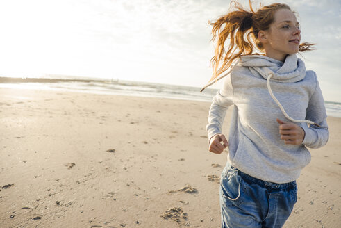 Netherlands, Zeeland, redheaded woman jogging on the beach - KNSF04207