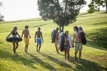 Eine Gruppe junger Leute, Jungen und Mädchen, mit Handtüchern und Schwimmflügeln in der Hand, geht schwimmen. - MINF00456