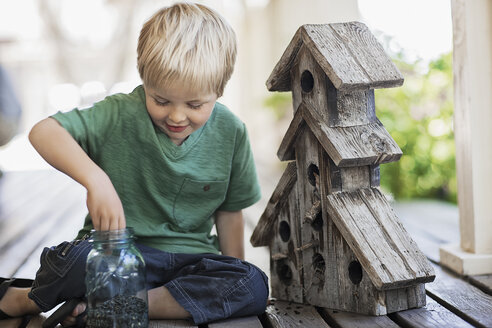 Ein Kind untersucht einen Käferkasten auf einer Veranda. - MINF00478
