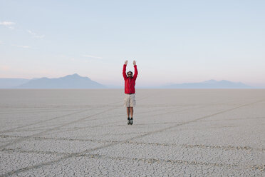 Ein Mann springt in der flachen Wüste oder Playa oder Black Rock Desert, Nevada, in die Luft. - MINF00501