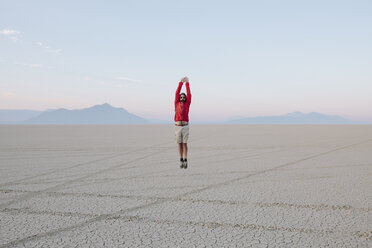A man jumping in the air on the flat desert or playa or Black Rock Desert, Nevada. - MINF00502