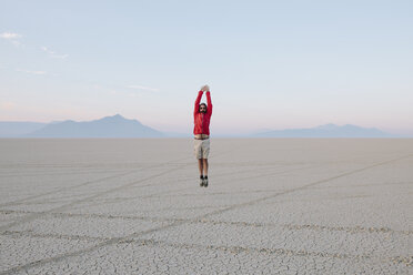 Ein Mann springt in der flachen Wüste oder Playa oder Black Rock Desert, Nevada, in die Luft. - MINF00502