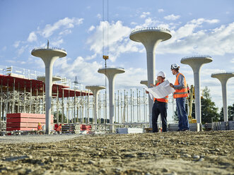 Workers on construction site looking at blueprint with the architect - CVF00973