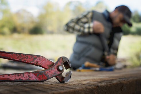 Ein Mann bereitet das Holz vor, indem er alle Nägel und Bolzen entfernt. - MINF00520