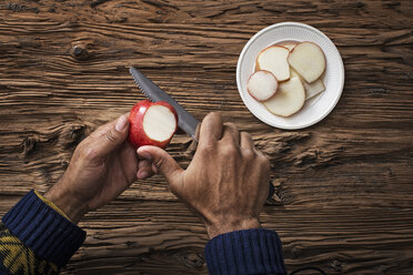 A person holding and slicing sections of a red skinned apple. - MINF00526