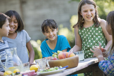 Eine Gruppe von Kindern sitzt an einem Tisch und isst frisches Obst und Salat. - MINF00638