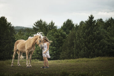 Ein junges Mädchen mit einem Palomino-Pony auf einem Feld. - MINF00686