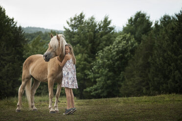 Ein junges Mädchen mit einem Palomino-Pony auf einem Feld. - MINF00687