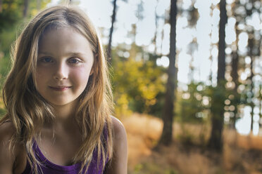 A young girl with long blonde hair in woodland in the fresh air, looking at the camera. - MINF00690