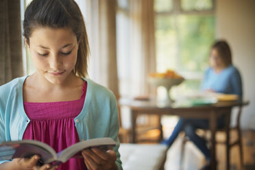 Eine junge Frau liest ein Buch in einer traditionell eingerichteten Wohnung. - MINF00691