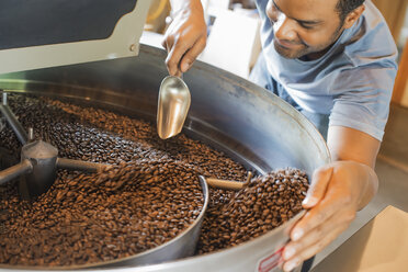 Maschinen in einer Halle zur Verarbeitung von Kaffeebohnen, die unter Aufsicht eines jungen Mannes Kaffeebohnen erhitzen und rösten. - MINF00695