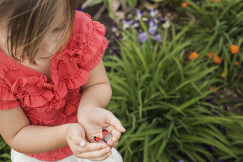 Ein junges Mädchen betrachtet einen bunten Schmetterling im Gras. - MINF00698