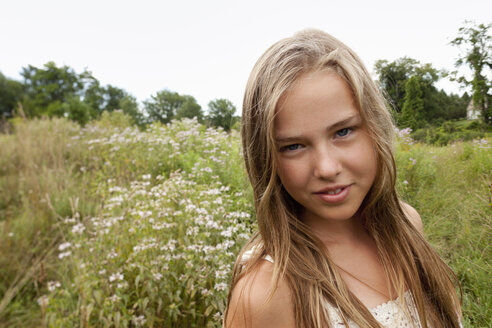 Ein junges Mädchen mit langen blonden Haaren spielt im hohen Gras. - MINF00701