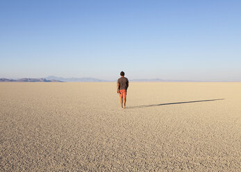 Mann geht durch eine flache Wüstenlandschaft - MINF00725