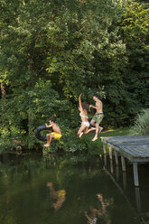 Drei Jungen springen vom Steg in ein stilles Wasserbecken. - MINF00757