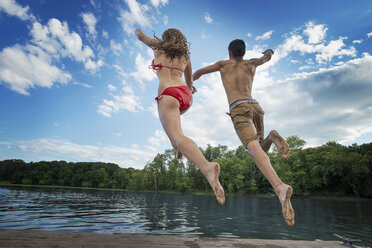 Zwei junge Leute, ein Junge und ein Mädchen, rennen und springen von einem Steg in einen See oder Fluss. - MINF00764
