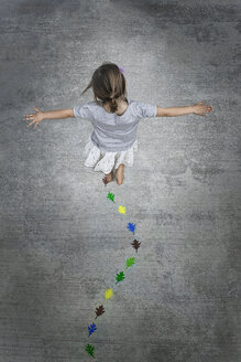 View from overhead of a child creating and walking along a line of coloured leaf shapes. - MINF00772