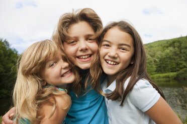 Drei junge Mädchen, Freundinnen nebeneinander, posieren für ein Foto in der freien Natur. - MINF00778