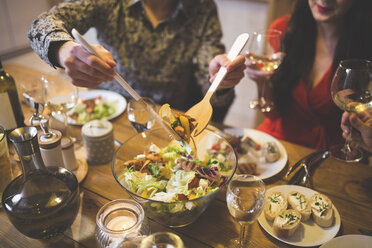 Mann serviert Salat beim Abendessen mit Familie und Freunden - AWF00110