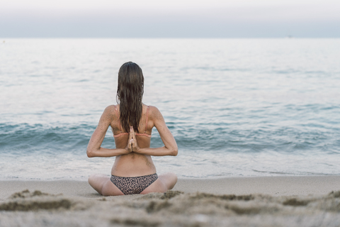 Schöne Frau am Strand übt Yoga, lizenzfreies Stockfoto