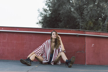 Woman wearing unbuttoned striped shirt sitting on ground - AFVF00864