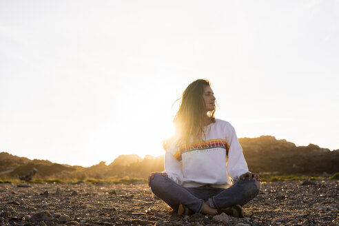Junge Frau am Strand sitzend, bei Sonnenuntergang - AFVF00883